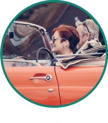A couple in their 60s ride in a red convertible